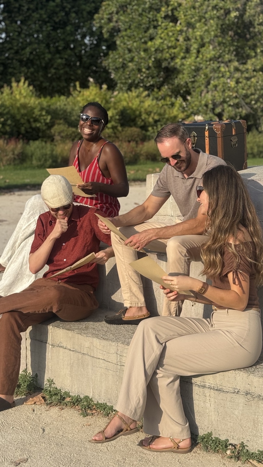 Plusieurs personnes réunies autour d’un journal Timeless, à côté de la malle